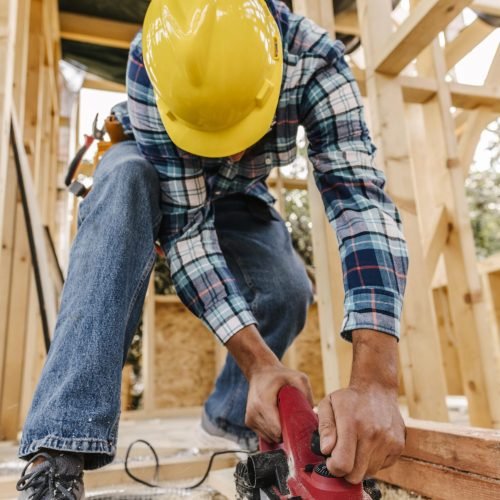 trabajador-de-la-construccion-con-casco-lijando-pieza-de-madera